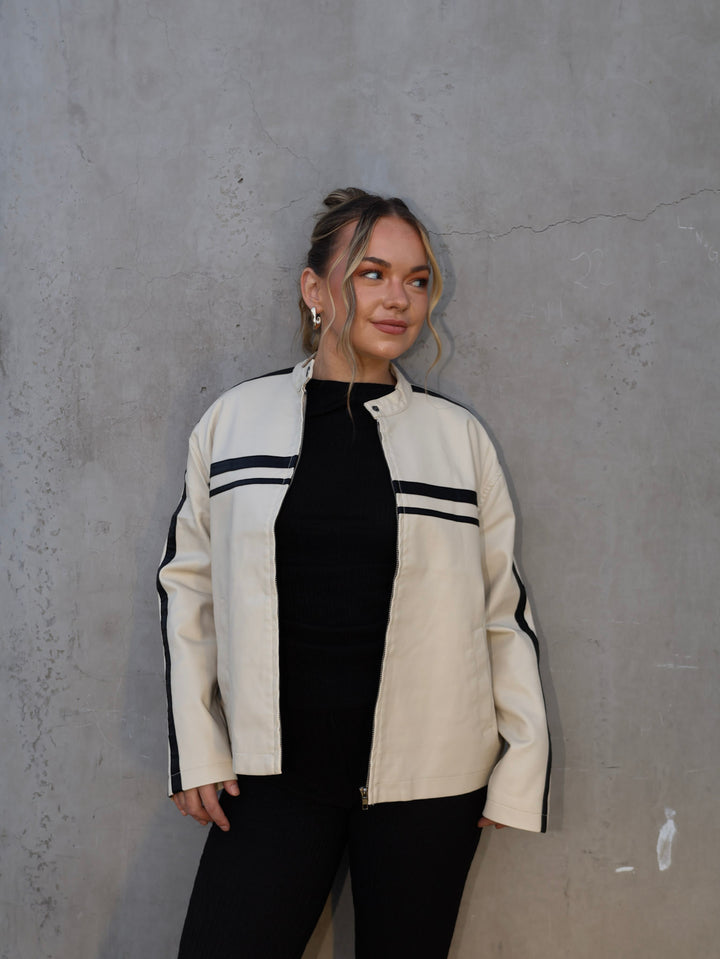 Person wearing a white jacket with black accents against a gray wall