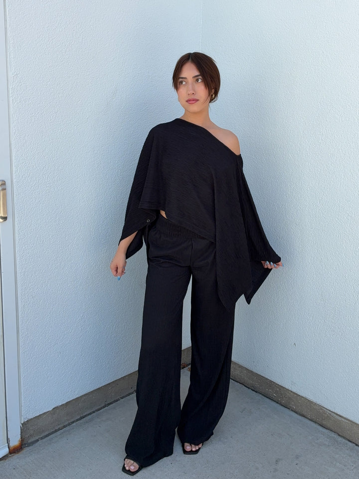 Woman wearing a black outfit against a light blue wall.