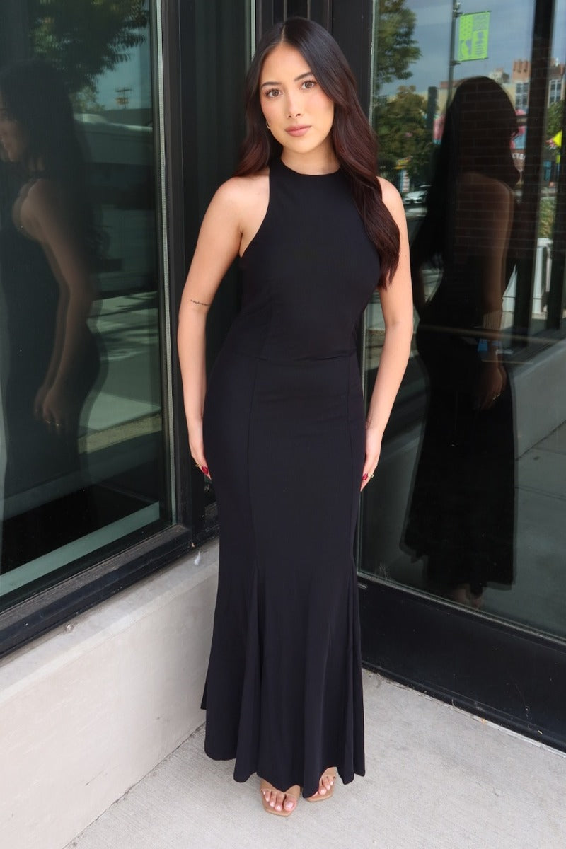 Model wearing the black Midnight mesh high halter neck maxi dress in front of a storefront window, full length front view