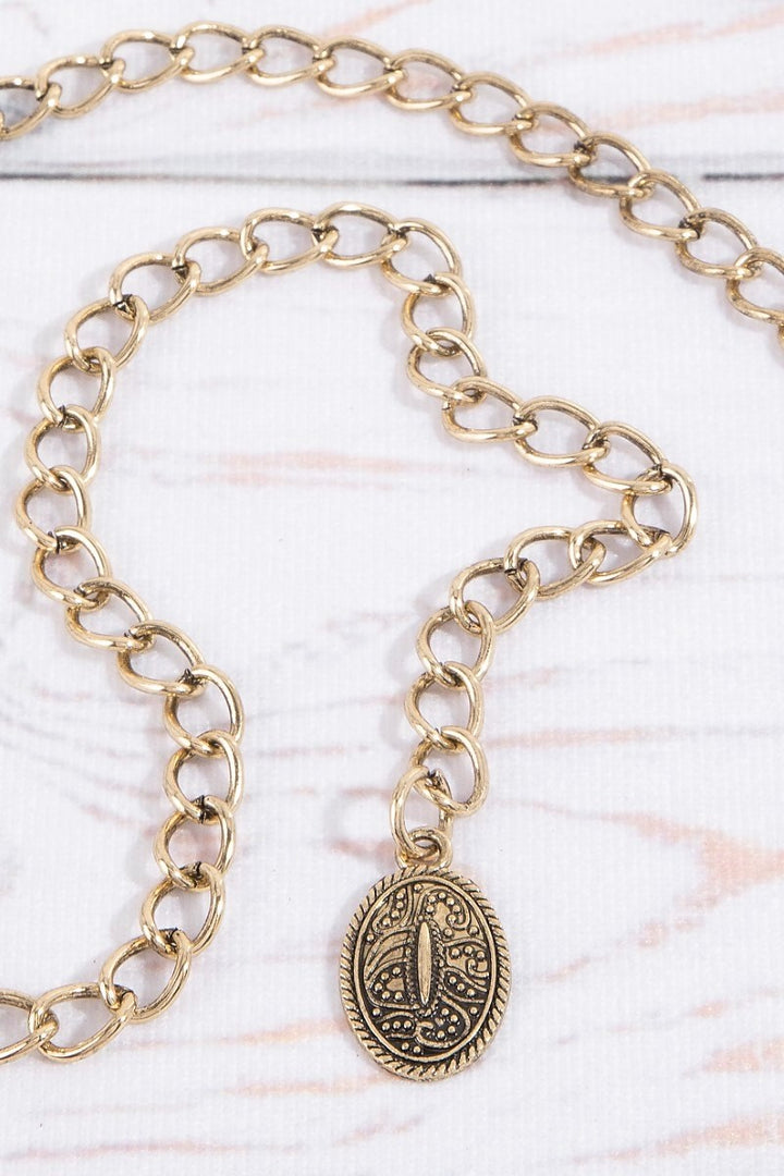 The Concho Disc Chain Belt in Antique Gold - Close-Up of Adjustable Curb Chain Tail with Decorative Oval Charm Pendant Finish