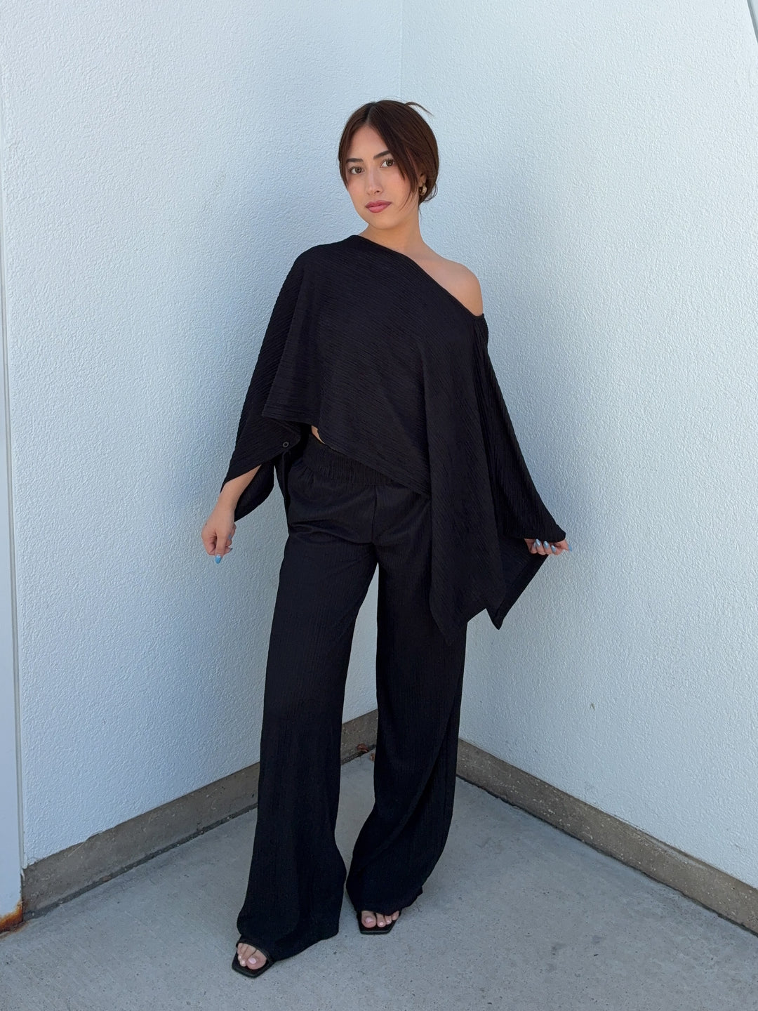 Person wearing a black outfit against a light blue wall.