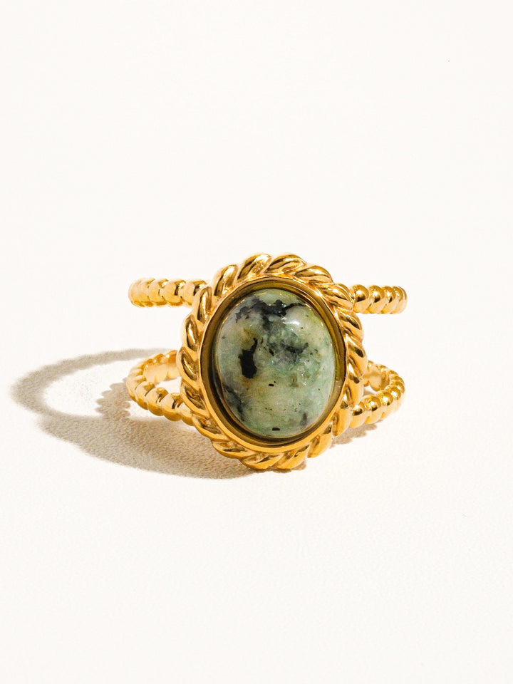 The Peacock Stone Rope Bezel Double Band Ring in 18K Gold - Product Shot on Cream Background Showing Front View of Oval Peacock Stone in Rope-Twist Bezel with Double Rope-Twist Band & Open Adjustable Back