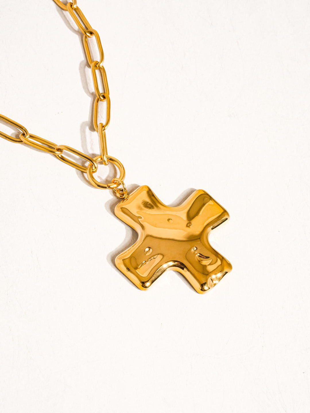 The Hammered Cross Paperclip Chain Necklace in 18K Gold - Close-Up Product Shot on White Background Showing Oversized 3D Hammered Puffy Cross Pendant Hanging from Chunky Gold Paperclip Link Chain