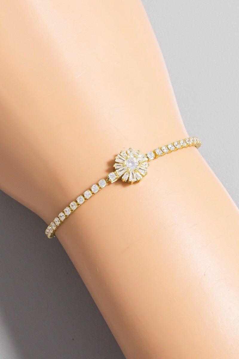Gold bracelet with a sunflower design on a person's wrist against a neutral background