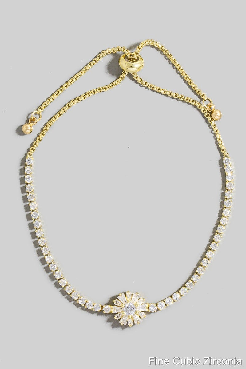Gold bracelet with a floral clasp on a gray background