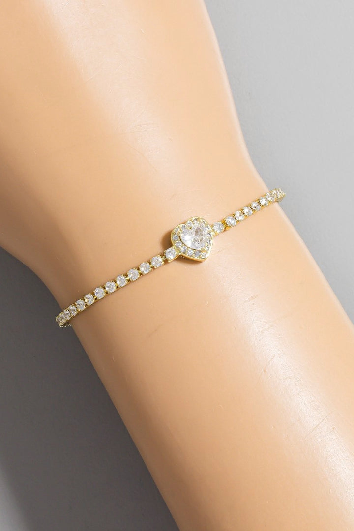 Gold bracelet with a central diamond on a person's wrist against a neutral background