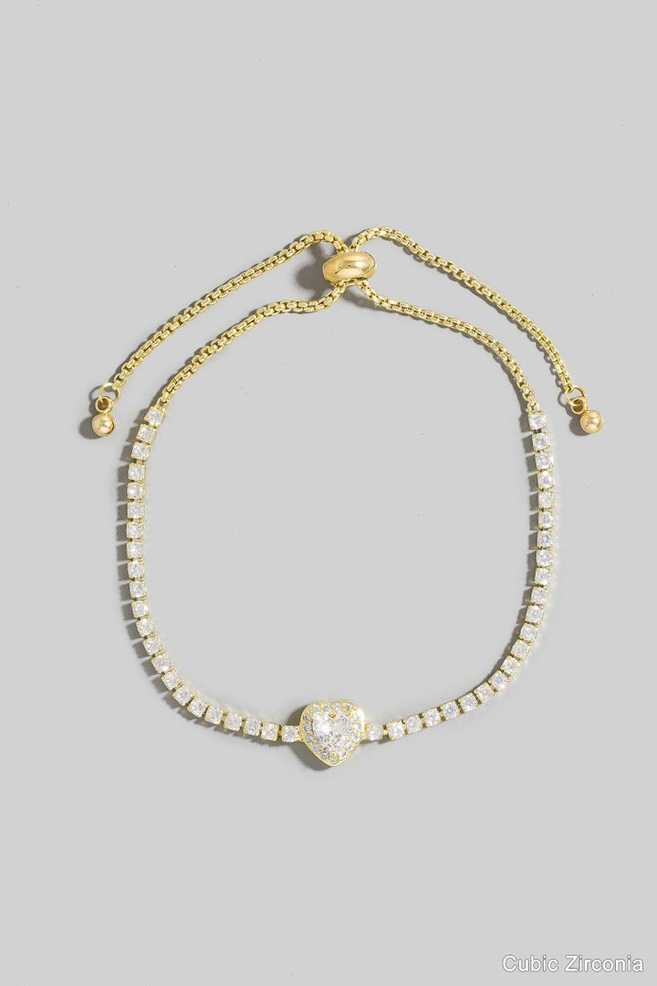 Gold bracelet with heart-shaped clasp on a gray background