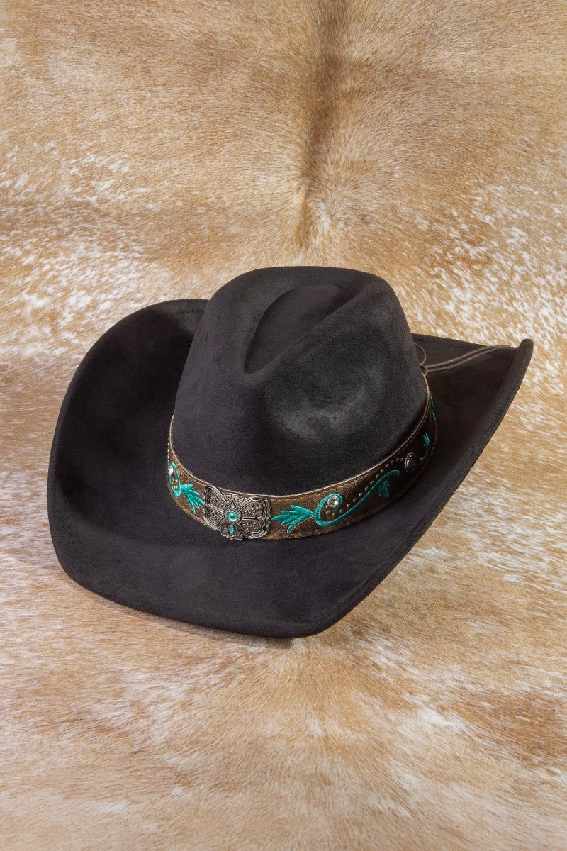 The Concho Embroidered Strap Cowboy Hat in Chocolate - Three-Quarter View on Cowhide Surface Showing Dark Brown Felt Body, Turquoise Floral Embroidered Hatband & Ornate Silver Concho Centerpiece