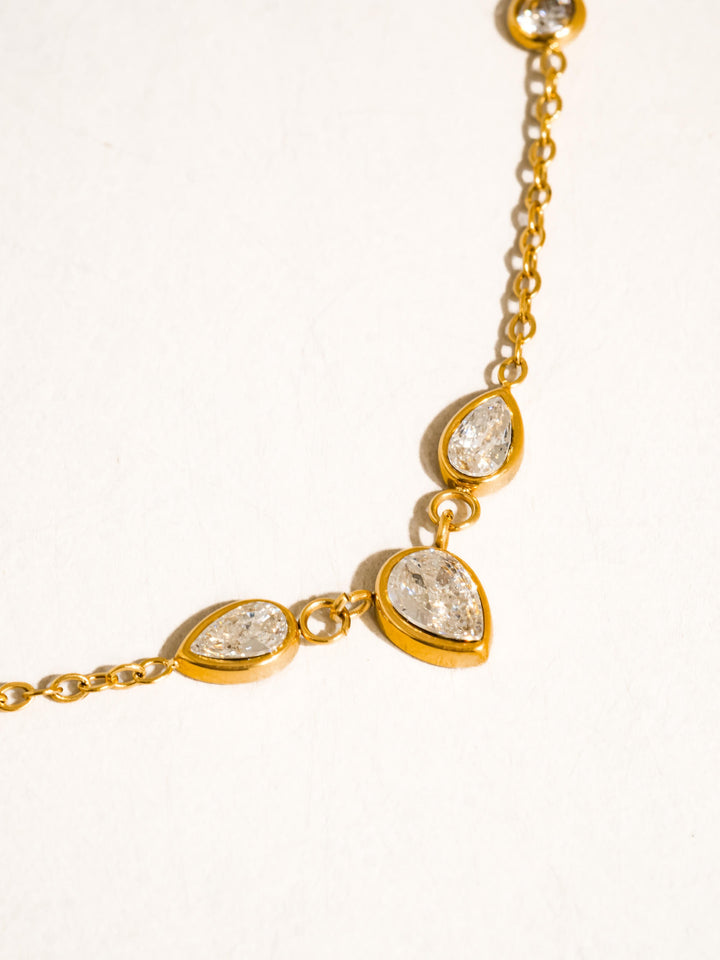 The CZ Teardrop Station Layering Necklace in 18K Gold - Detail Product Shot on White Background Showing Close-Up of Alternating Round & Teardrop CZ Bezel Stations with Individual Gold Bezel Settings & Fine Cable Chain