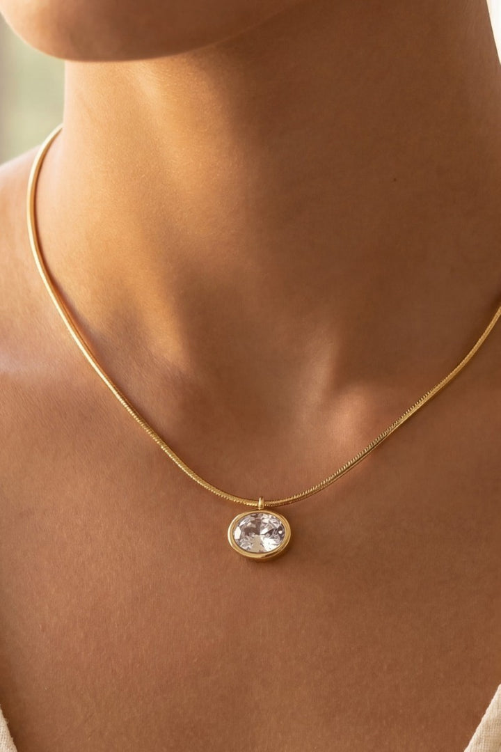 The Oval CZ Bezel Snake Chain Necklace in Gold Dipped - On-Model Close-Up Showing Flat Gold Snake Chain Lying Against Décolleté with Oval CZ Bezel Pendant at Center