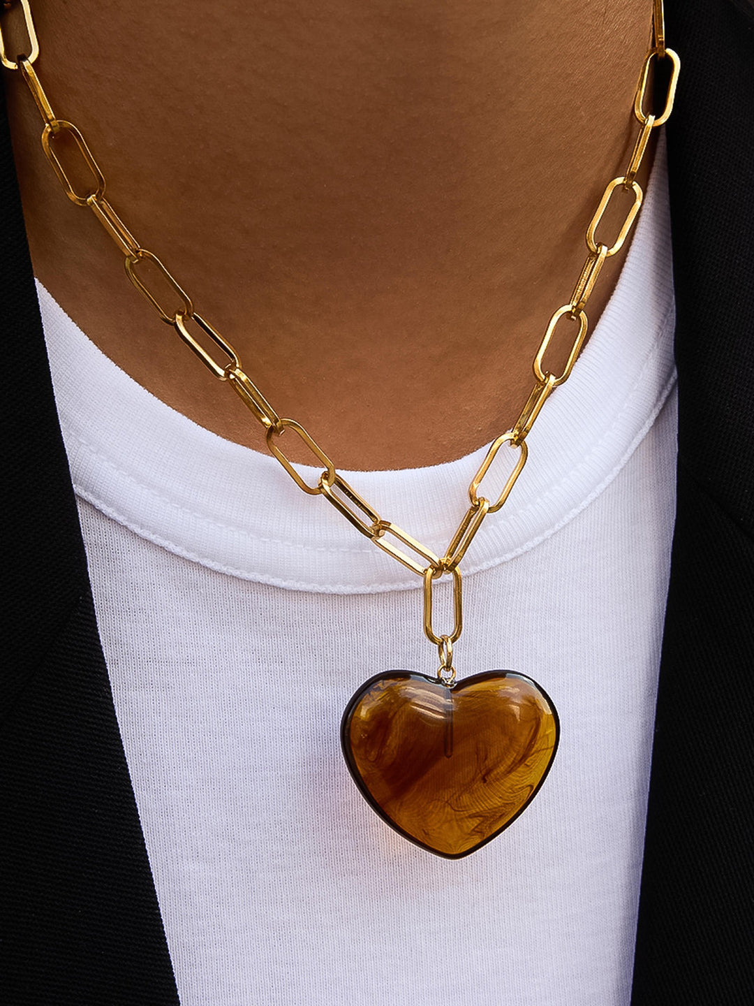The Resin Heart Paperclip Chain Necklace in 18K Gold Amber Tortoise - On-Model Shot Showing Oversized Amber Tortoise Resin Heart Pendant on Chunky Gold Paperclip Chain Against White Scoop-Neck & Black Blazer