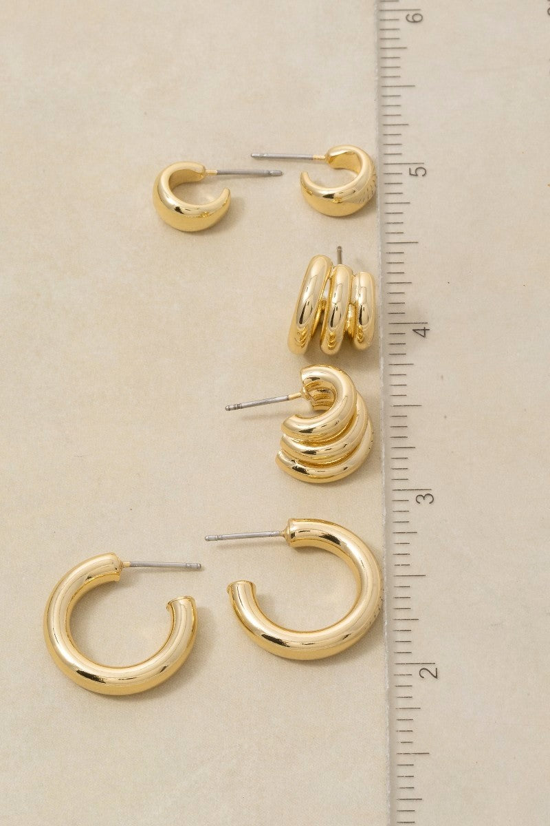 The Columbus Triple Coil Hoop Earrings in 18K Gold Dipped - Size Reference Flat Lay on Cream Background Against Ruler Showing All Four Hoop Sizes Including Triple Coil at Approximately 1.5 Inches