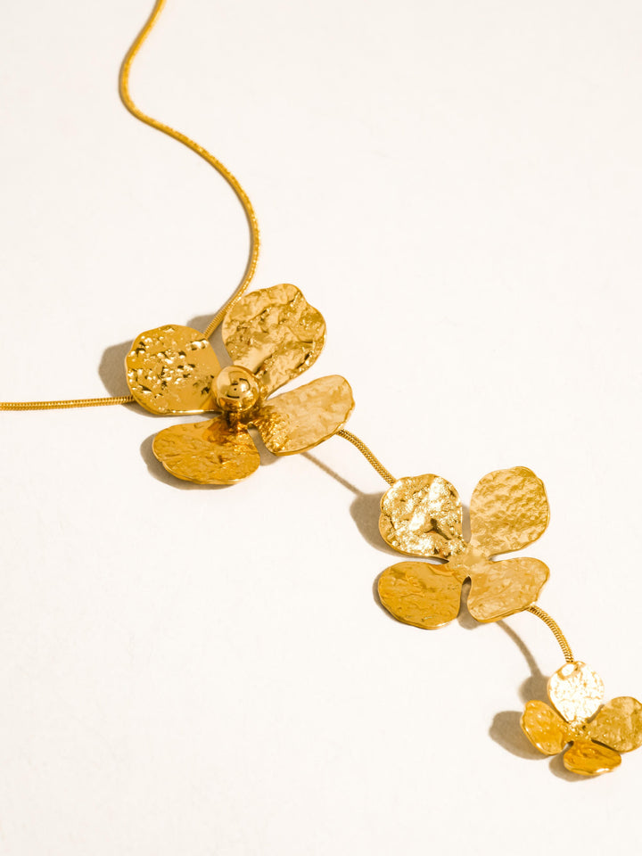 The Triple Hammered Flower Lariat Necklace in 18K Gold - Close-Up Product Shot on White Background Showing Three Cascading Hammered Flower Pendants in Descending Sizes with Dimpled Petal Texture Detail