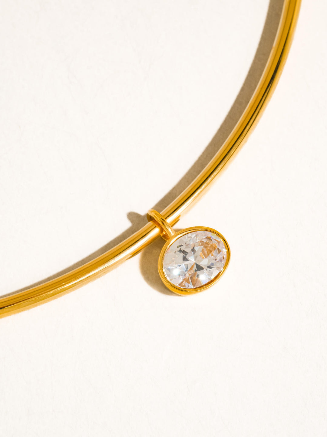 The Classic CZ Bezel Wire Choker in 18K Gold - Close-Up Product Shot on Cream Background Showing Double-Wire Gold Choker with Single Oval CZ Bezel Drop Charm at Center