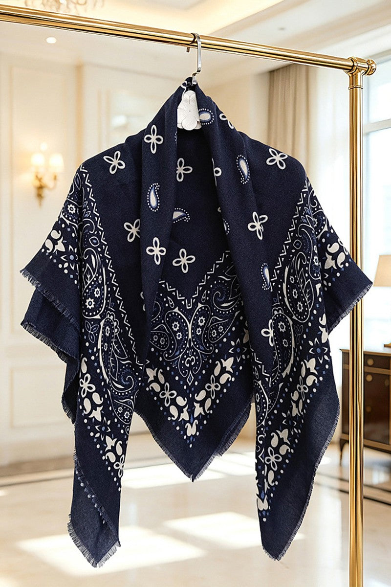A navy blue bandana scarf with white printed paisley and floral patterns, hanging on a gold clothing rack in a bright, elegant room.