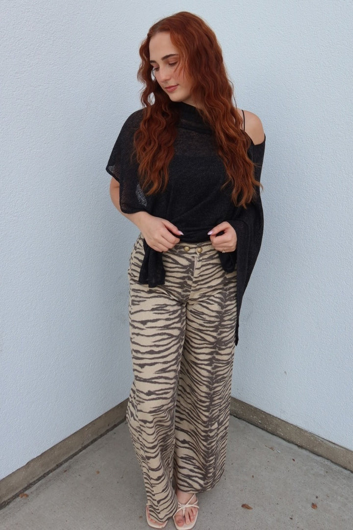 Model wearing the Tiger print belted wide leg woven pants with a black poncho top, looking down