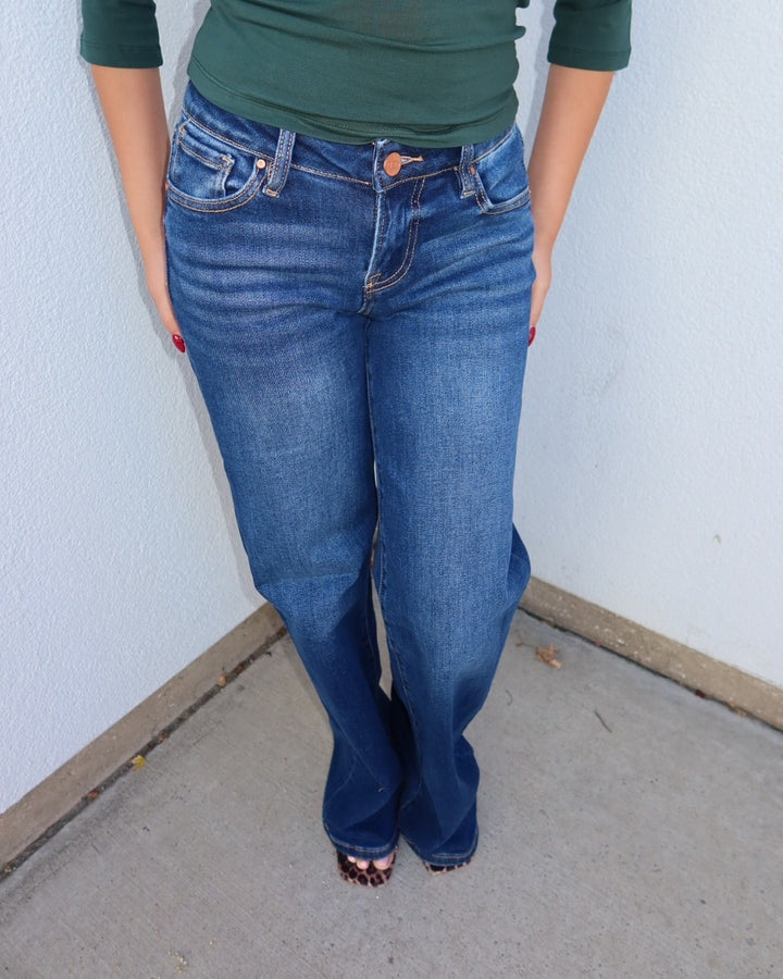 Front close-up of the Waltman dark wash wide leg jeans showing the low rise waist and button fly, with a green top