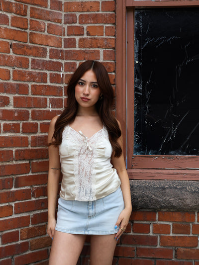 Woman standing against a brick wall with a broken window