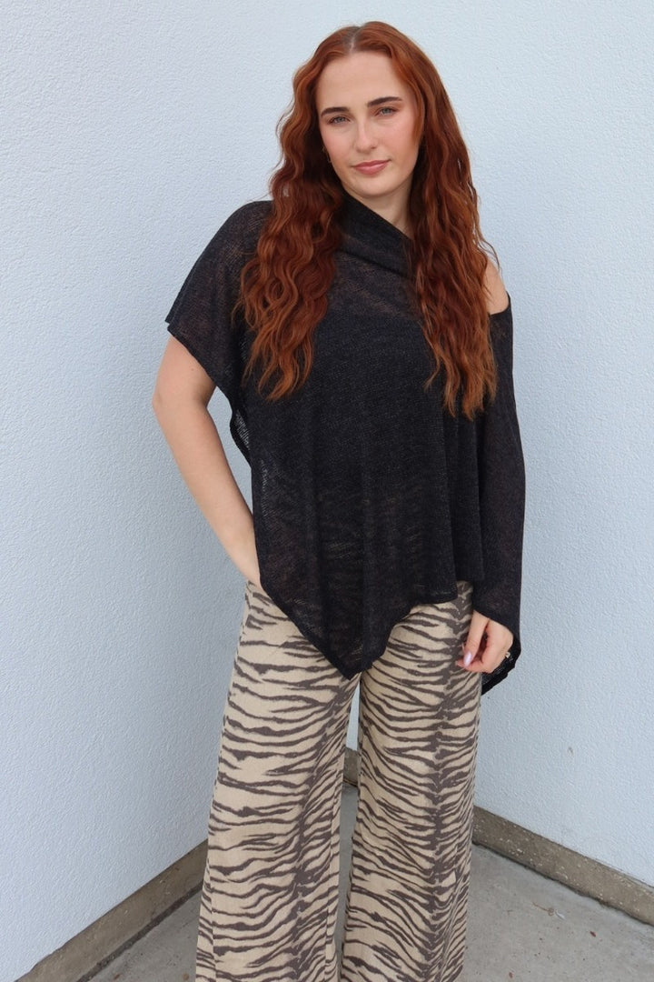 Model wearing the black Portofino sheer knit poncho top with hand on hip, front view