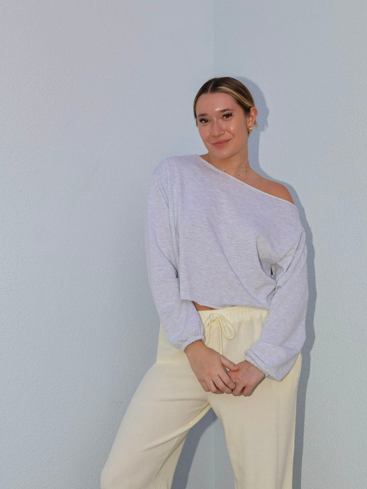 Person wearing a light purple sweater and beige pants against a plain background