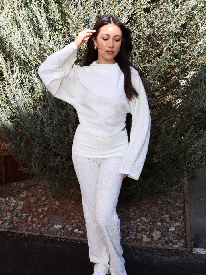 Person wearing a white outfit standing against a natural background