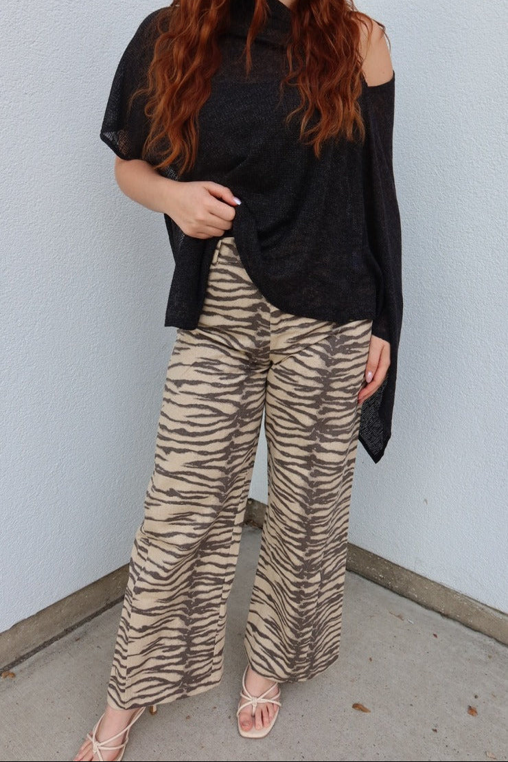 Model wearing the Tiger print belted wide leg woven pants with a sheer black poncho top and white strappy sandals