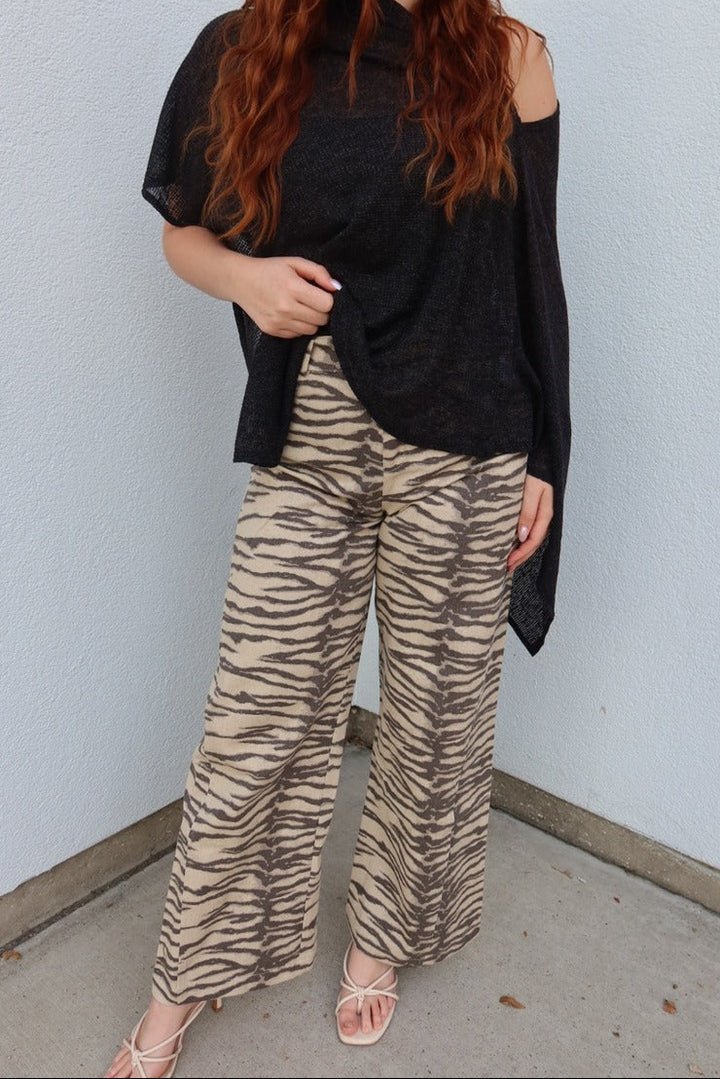 Model wearing the Tiger print belted wide leg woven pants with a sheer black poncho top and white strappy sandals