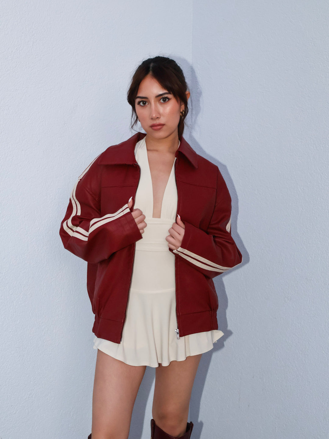 Woman wearing a maroon jacket with white stripes on a light blue background