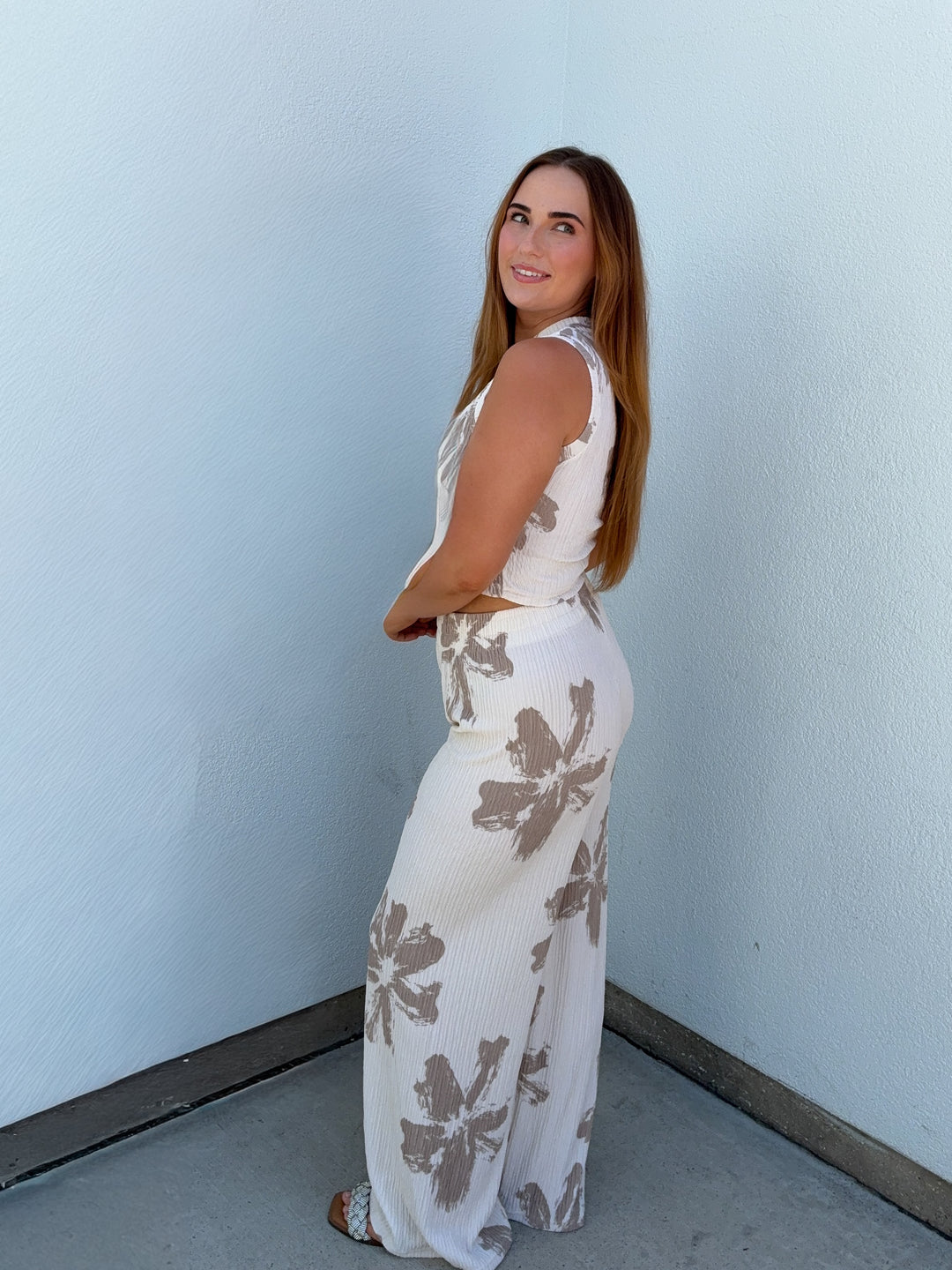 Woman wearing a white floral dress against a light blue wall.