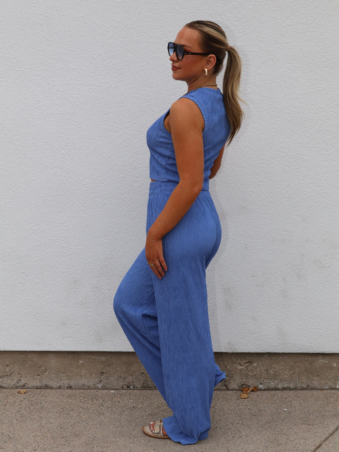 Woman wearing a blue jumpsuit against a white wall