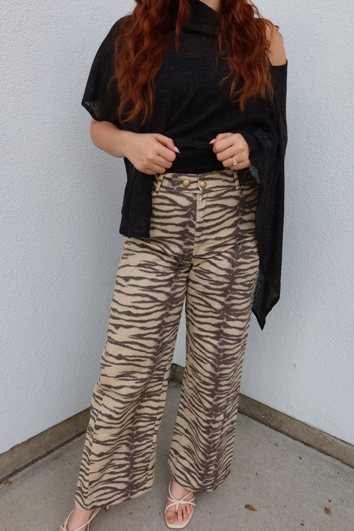 Front view of the Tiger print belted wide leg woven pants with a black top lifted to show the waistband