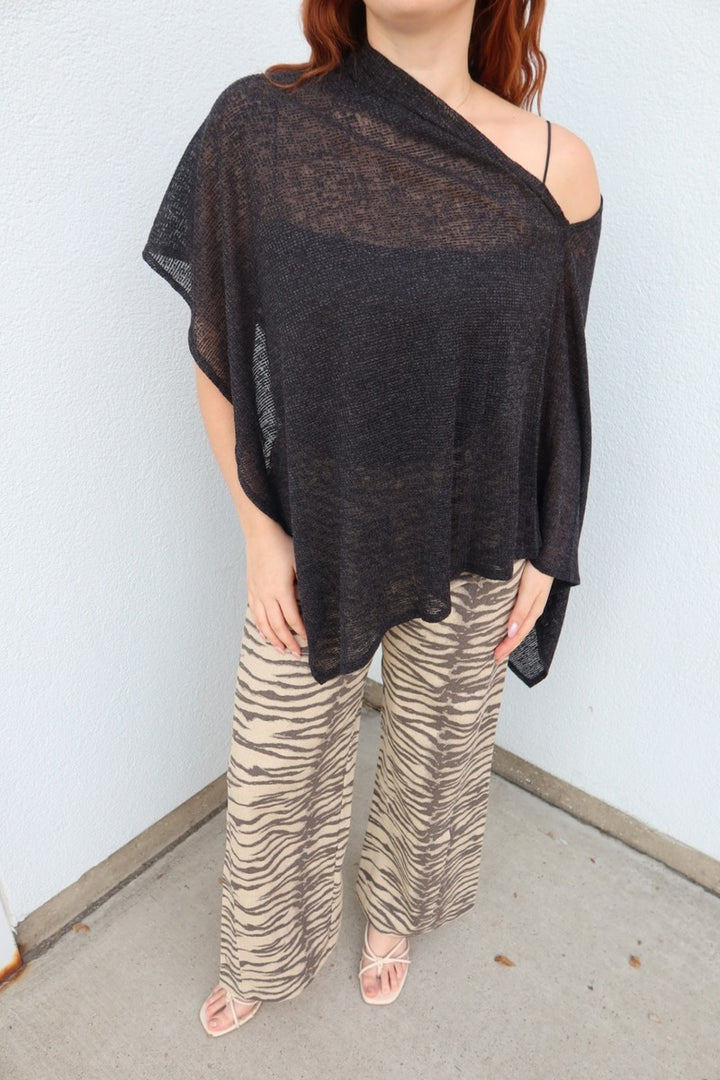 Close view of the asymmetric black Portofino sheer knit poncho top, showing the sheer knit and one-shoulder drape