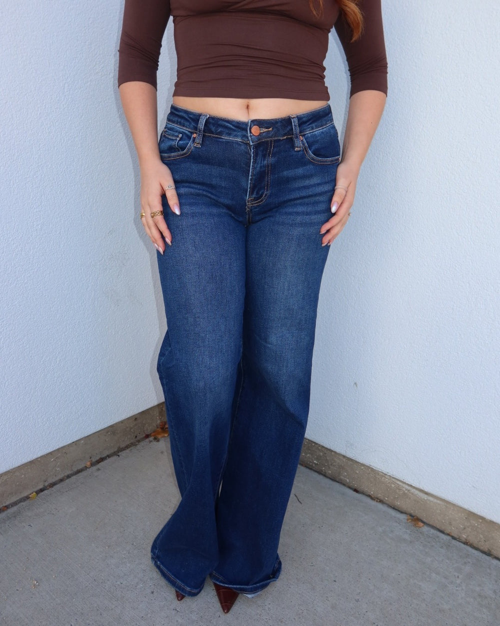 Close-up front view of the Waltman low rise dark wash wide leg jeans worn with a cropped brown top