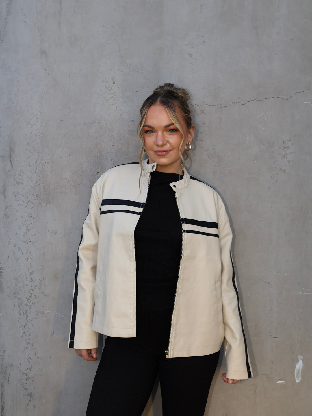 Person wearing a white jacket with black accents against a gray wall