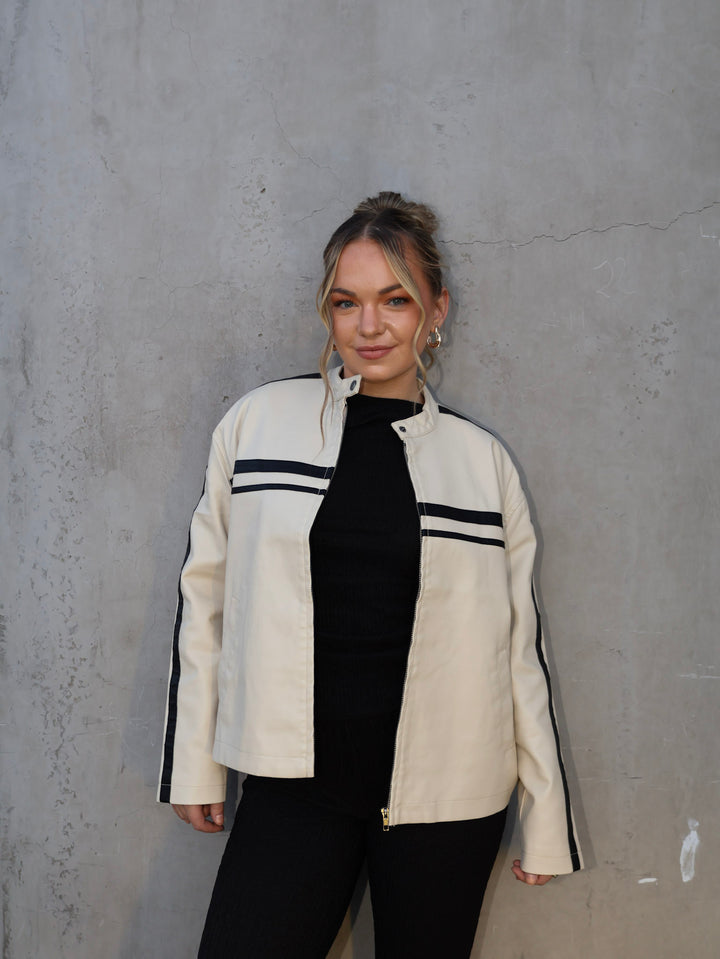 Person wearing a white jacket with black accents against a gray wall