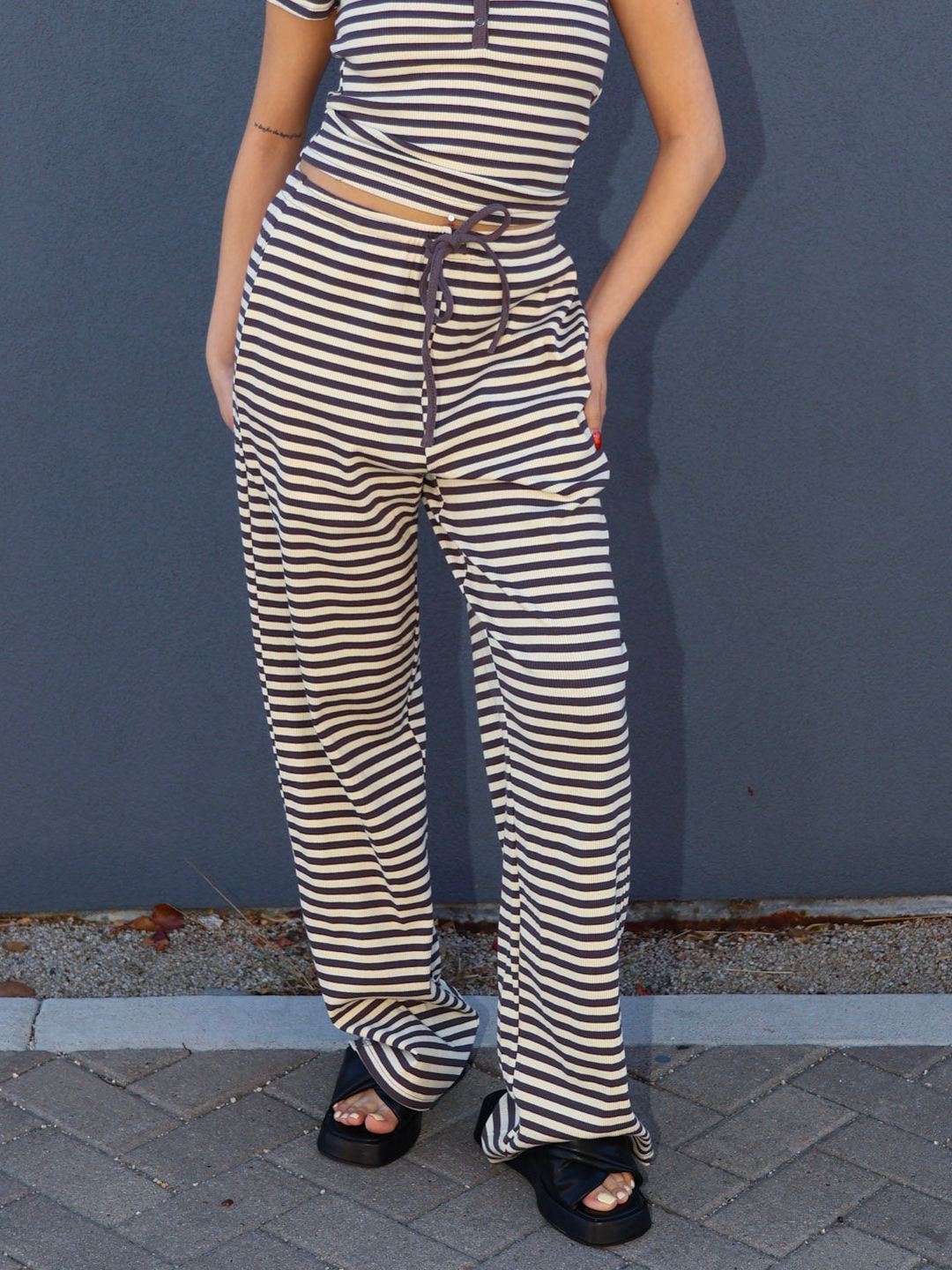 Person wearing a striped outfit standing against a blue wall.