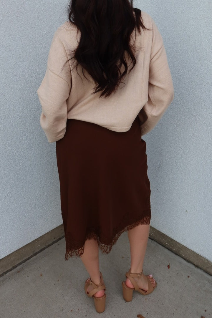 Back view of the brown Lucy asymmetric lace trim satin midi skirt, showing the lace trimmed hem