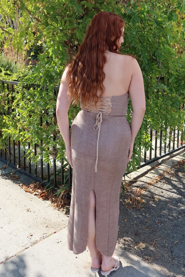 Back view of the taupe Karmen knitted maxi skirt, showing the back slit, worn with the lace-up corset top