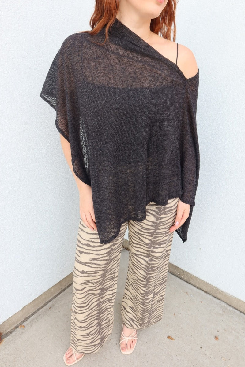 Close view of the black Portofino sheer knit poncho top layered over a black cami