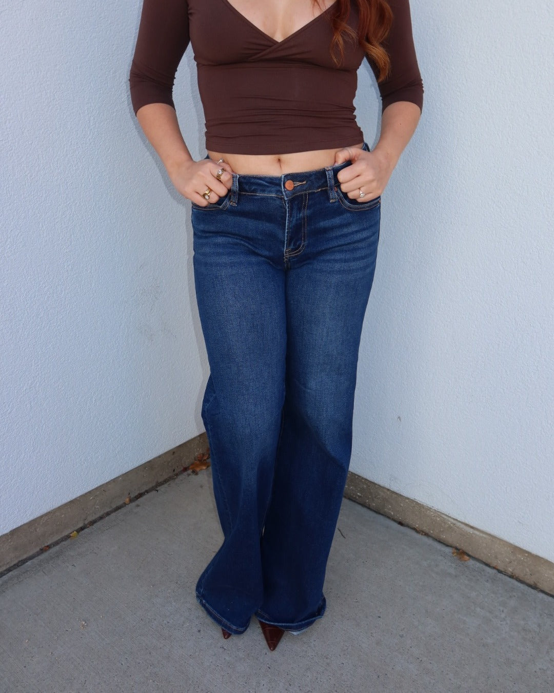 Close-up of the Waltman dark wash wide leg jeans showing the low rise waist, styled with a brown surplice top