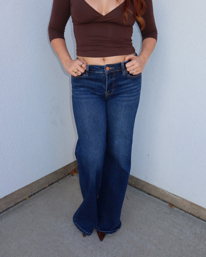 Close-up of the Waltman dark wash wide leg jeans showing the low rise waist, styled with a brown surplice top