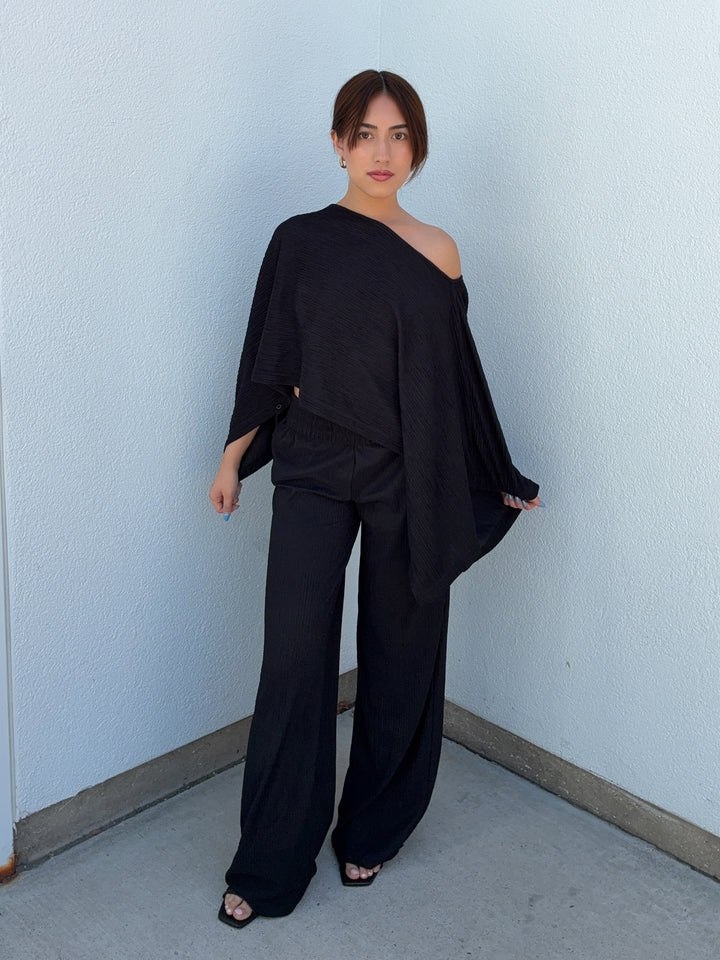 Woman wearing a black outfit against a light blue wall.