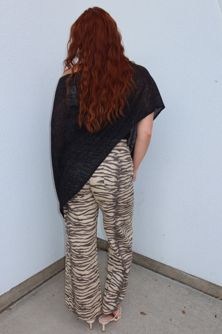 Angled back view of the Tiger print belted wide leg woven pants with a black poncho top