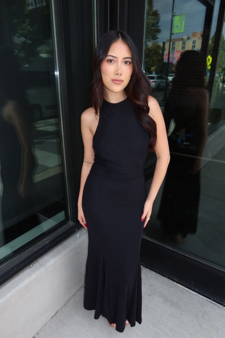 Model in the black Midnight mesh high halter neck maxi dress posed by a storefront window, full length front view