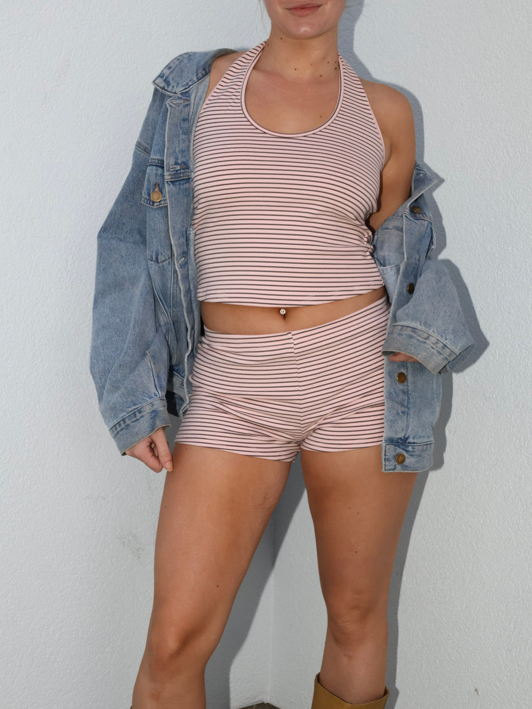 Person wearing a matching striped outfit with a denim jacket on a plain background