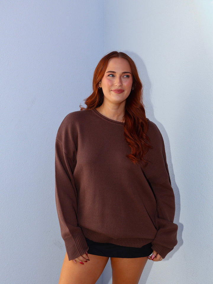 Woman wearing a brown sweater against a light blue background