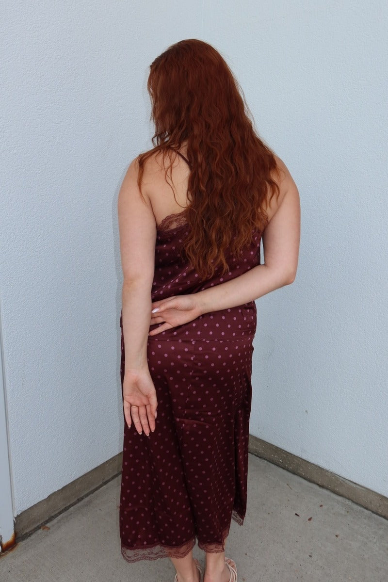 Back view of the burgundy Iris polka dot lace trim midi skirt, hand behind her back