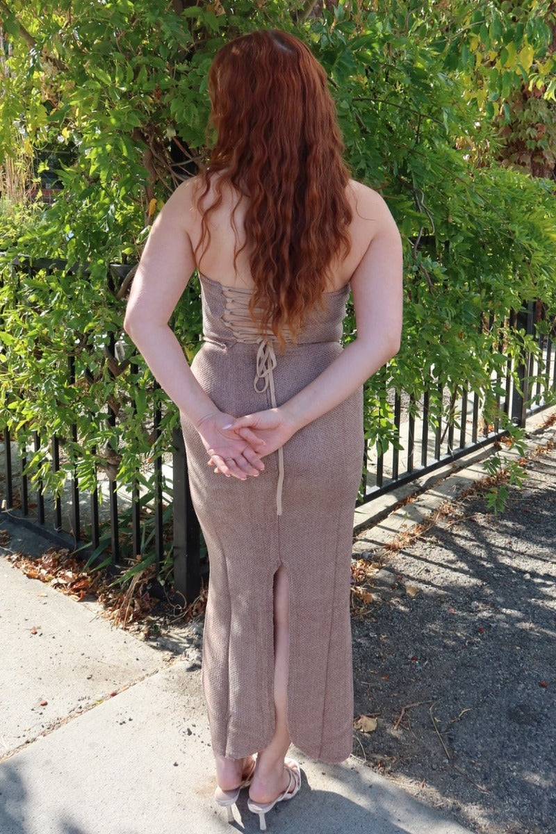 Back view of the taupe Karmen knitted maxi skirt, hands clasped behind, showing the back slit