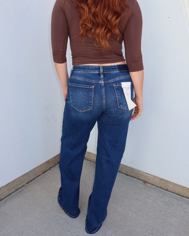 Back view of the Waltman low rise dark wash wide leg jeans with a brown top, hang tag on the back pocket