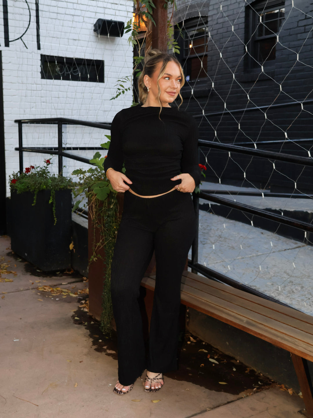 Woman in a black outfit standing in front of a black and white building.